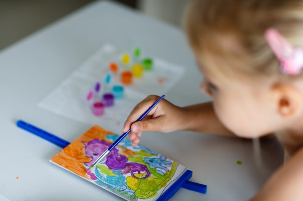 Art education for preschool kids. Little Caucasian girl five years old draws in kindergarten