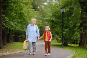 Beautiful gray-haired elderly lady accompanies or pick up baby from school.