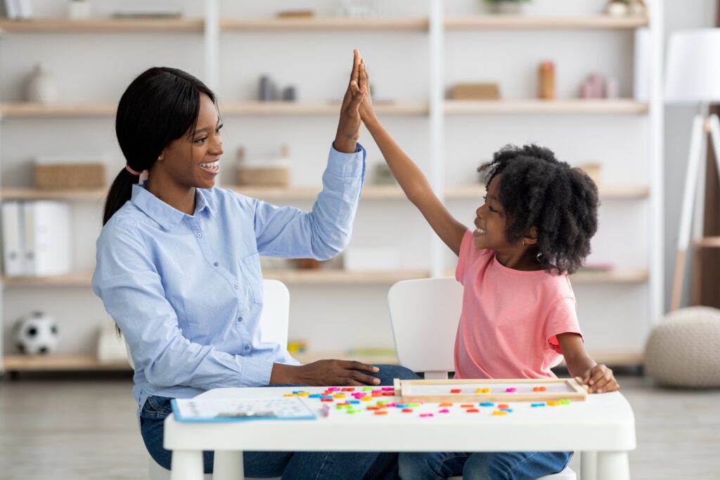 Happy little black girl giving her teacher high five